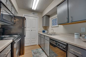 A kitchen with a black fridge and stove top oven.